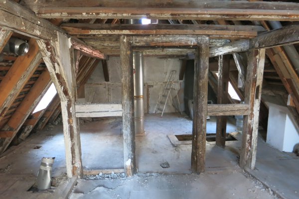 Dachboden, bei dem Holz-dachschrägen an den Seiten, alte Holzständerelemente und grauer Boden sichtbar sind