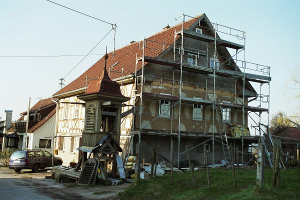 An der Giebelseite eingerüstetes Fachwerkhaus mit kleinem Glockentürmchen im Vordergrund